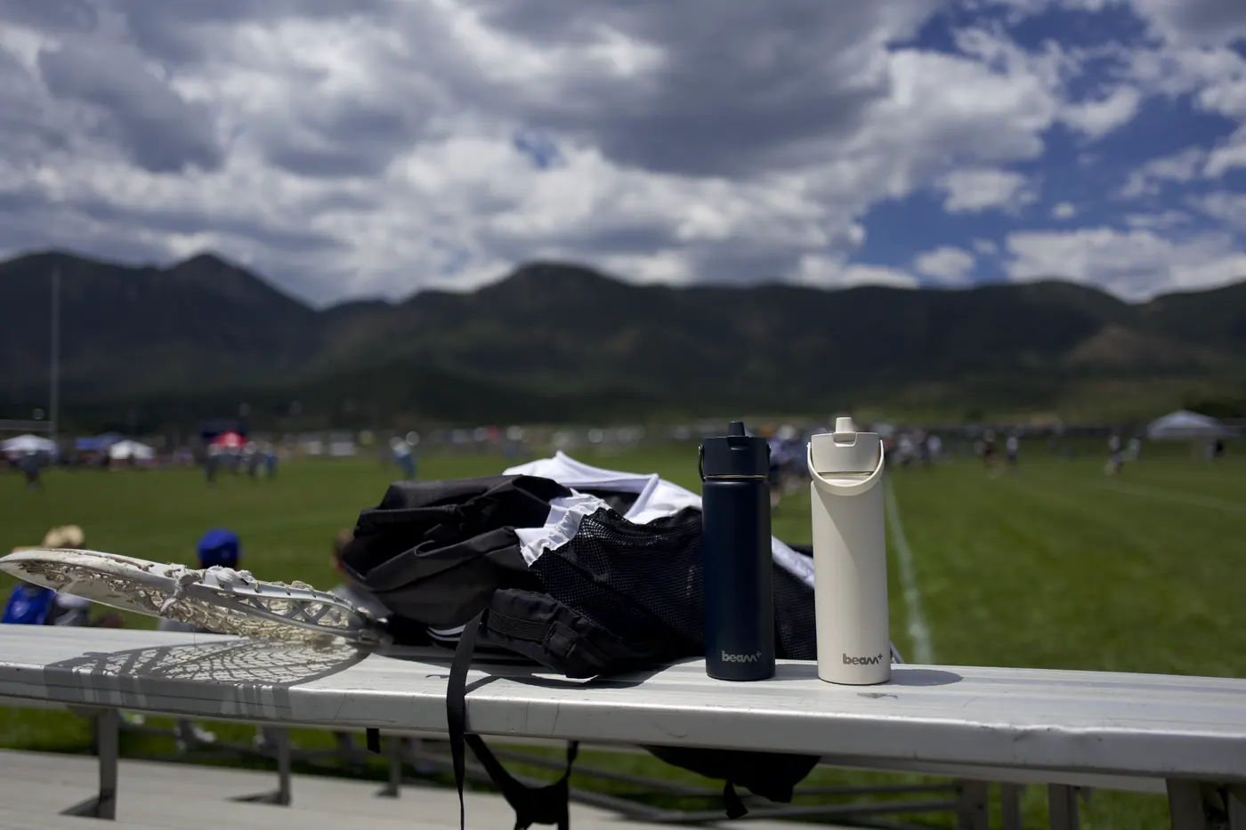 Deux bouteilles isothermes sur un gradin à côté d'un terrain de sport